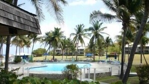 A pool area with palm trees and a building in the background. - Gentle Winds, St. Croix, U.S.V.I. - come unwind! (St. Croix)