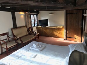 A hotel room with a bed, a wooden chair, a desk with a television, and a wooden door. - Pemberton House (Lincoln)