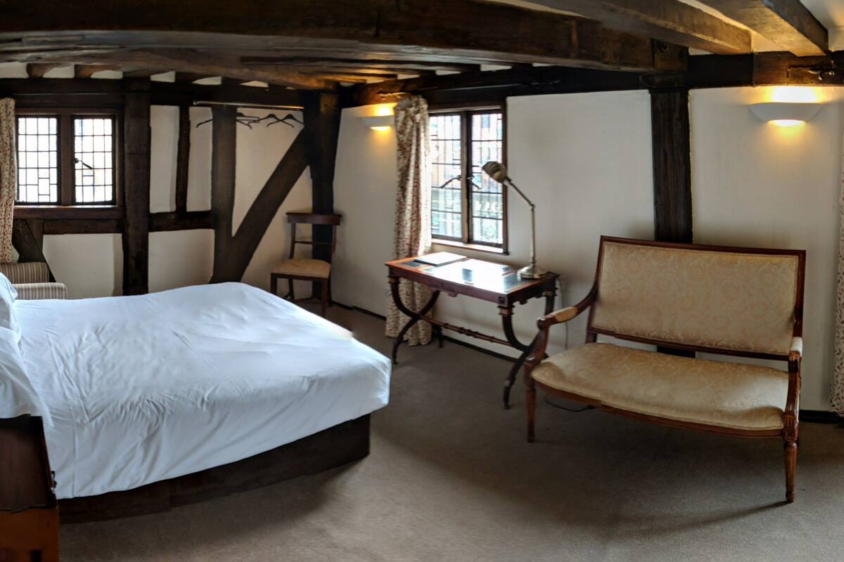 A traditional room with a bed, a desk, a chair, and a television.