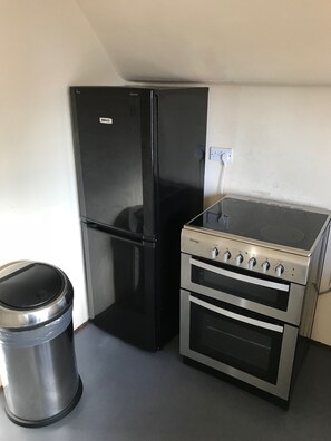 A kitchenette with a black refrigerator, a stainless steel trash bin, and a Prestige gas stove with two ovens. - Pemberton House (Lincoln)
