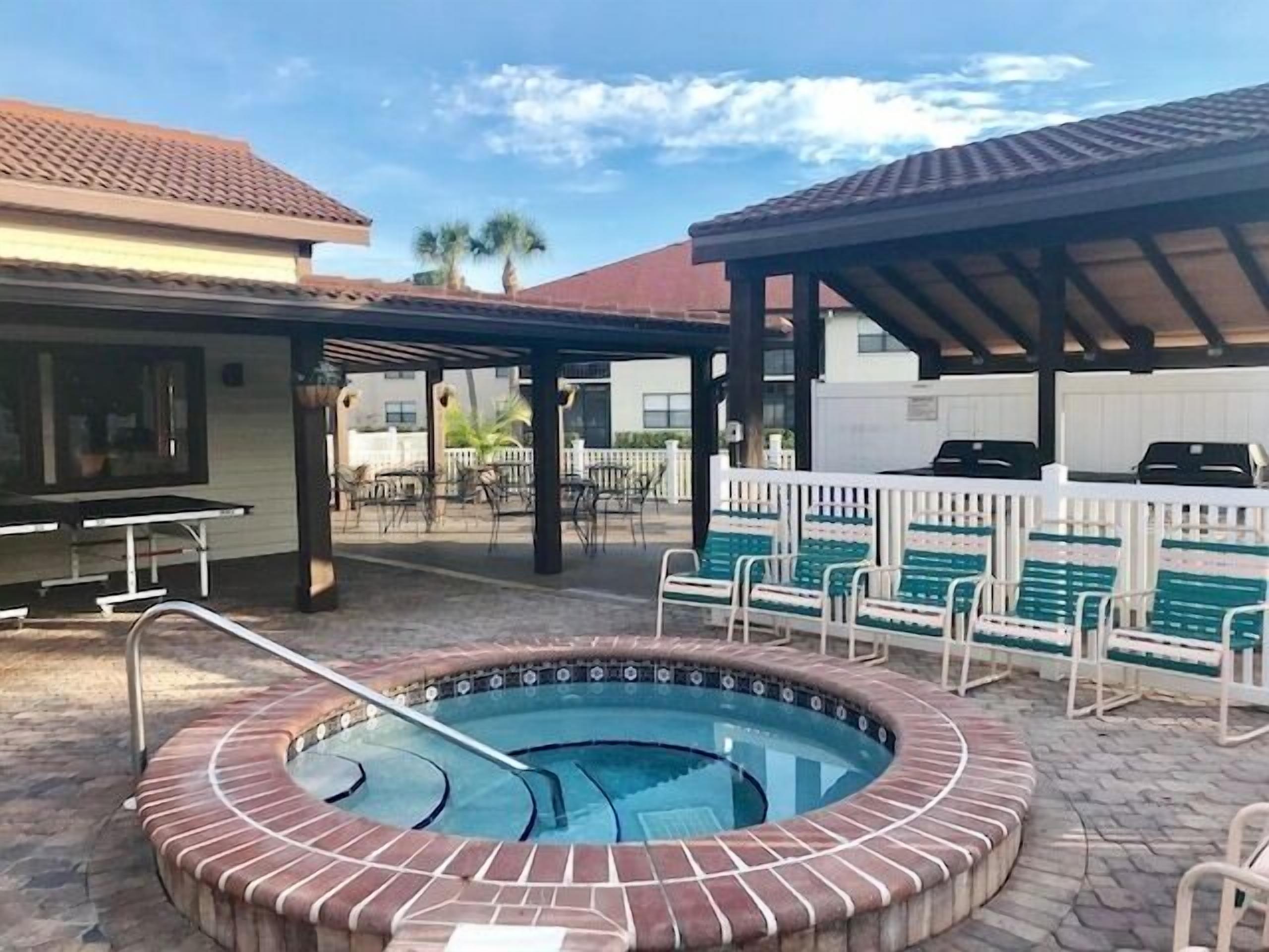 A pool area with a hot tub, outdoor seating, and a covered patio.