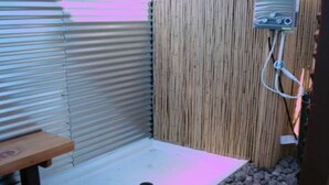 A small, enclosed shower area with a bench and a wooden wall. - "Lucille" Vintage Glamper Hideaway (Joshua Tree)