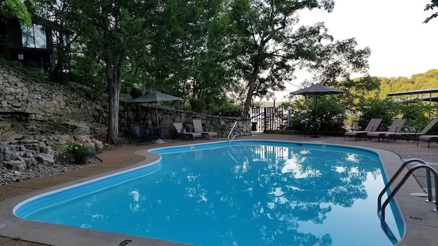 A swimming pool with a stone wall and lounge chairs.