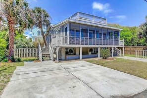 Une maison à deux étages dotée d’un balcon, d’un porche et d’un petit jardin.