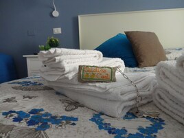 A neatly made bed with folded white towels, a keychain, and a small tag on the towel.