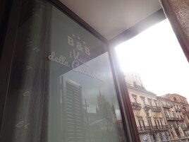 Una ventana con vistas a un edificio histórico y un cartel que dice "B&B della Città".