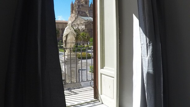 Vista desde un balcón con barandilla de hierro forjado, que da a un edificio histórico de arquitectura detallada.