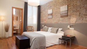 Une chambre à coucher moderne avec un mur en briques, un grand lit, une table de chevet et une chaise.
