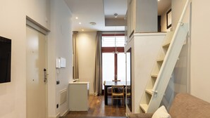 A modern interior with a wooden floor, a sofa, a dining table, and a staircase. - Uma Suites Barceloneta Beach (Barcelona)