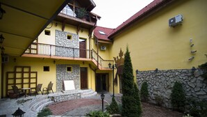 Un edificio amarillo con fachada de piedra, un balcón y un pequeño patio con una fuente.