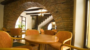 Un comedor con un arco de ladrillo, sillas de madera y una mesa redonda.