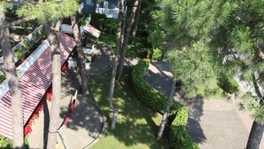 A courtyard with a covered seating area, surrounded by trees and a brick pathway. - Hotel Friuli (Lignano Sabbiadoro)