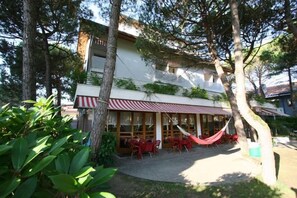A building with a red and white striped awning, outdoor seating with red chairs, and a hammock.
