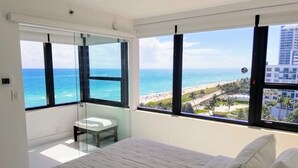 Una camera da letto con un letto grande, un bagno piccolo e vista sulla spiaggia e sull'oceano.