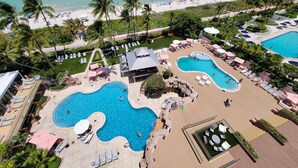 Un resort con diverse piscine, lettini prendisole e spiaggia.