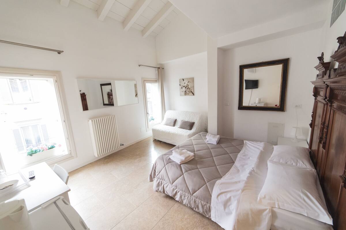 A bedroom with a bed, a chair, a desk, and a dresser.