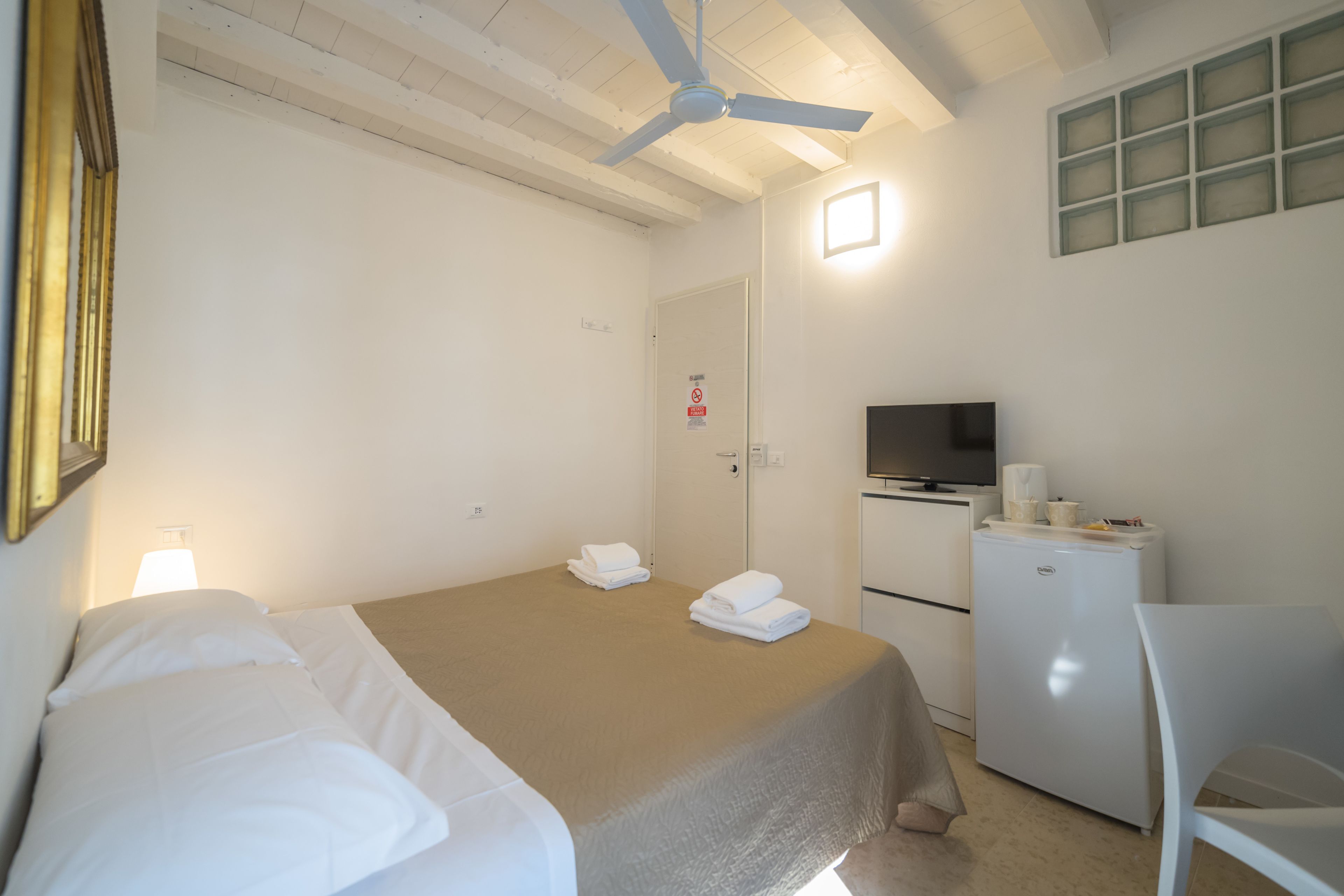 Ett hotellrum med en säng, ett skrivbord, en tv och ett kylskåp.