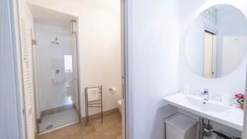 Un baño con ducha de vidrio, lavamanos blanco y espejo.