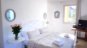 Ein ordentlich eingerichtetes Schlafzimmer mit Bett, Nachttisch, Lampe und Fernseher.