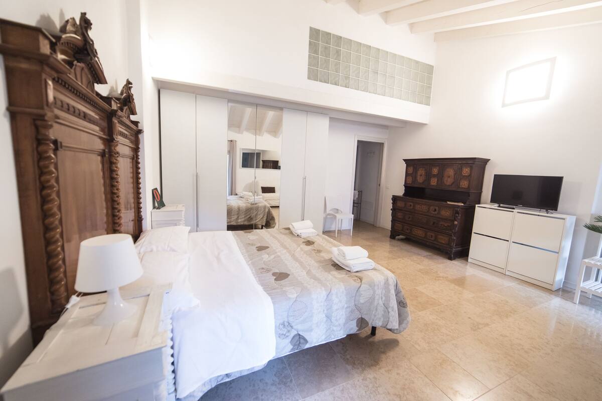 A hotel room with a bed, a dresser, a television, and a mirror.