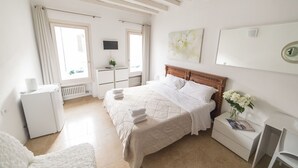 A bedroom with a bed, bedside table, and a small white dresser. - Academia Resort (Bergamo)
