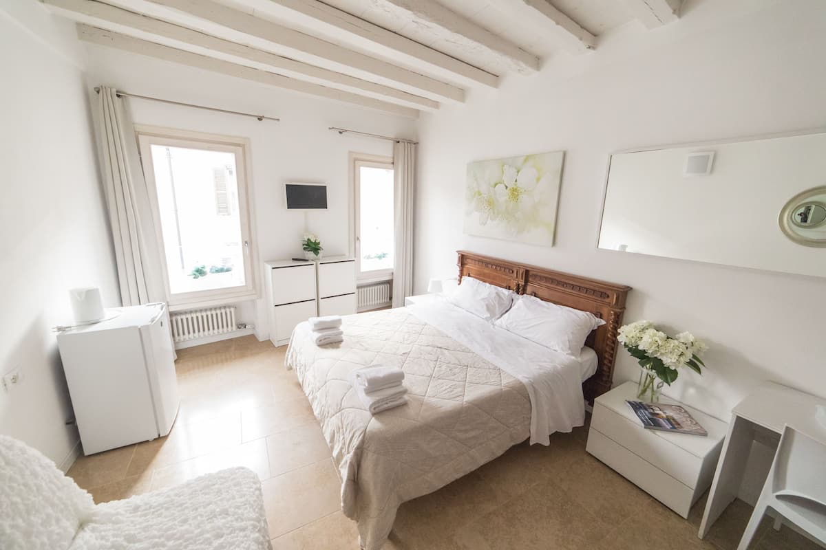 A bedroom with a bed, bedside table, and a small white dresser.