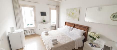Un dormitorio con cama, mesita de noche y una cómoda blanca.
