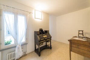 A room with a window, a radiator, a wooden desk, and a small table.
