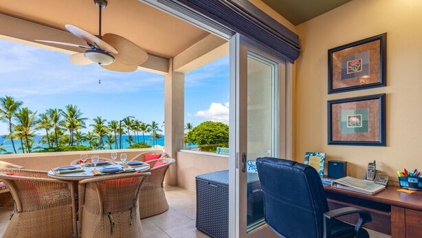 A balcony with wicker furniture, a desk with office supplies, and framed pictures on the wall. - Aloha Condos, Beach Villas at Kahaluu, Villa 1-202, Beach View, AC (Kailua Kona)