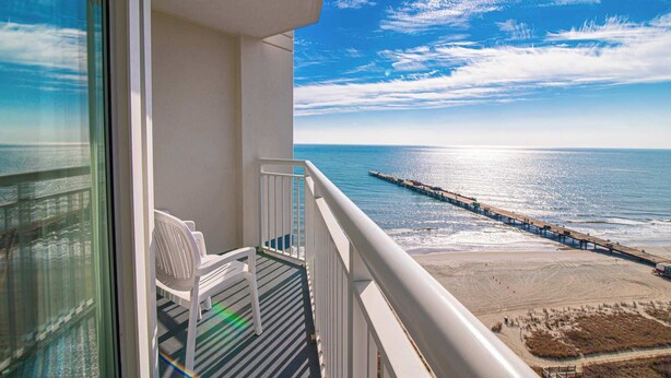 A balcony with a view of the ocean, a pier, and a beach. - Ocean View Beach Suite w Lazy River (Myrtle Beach)