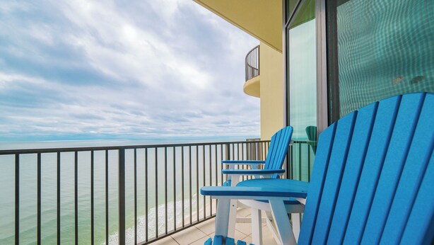 A balcony with two blue chairs and a yellow wall. - LAZY RIVER! Three Bedroom Condo @ Phoenix West #2607 (Orange Beach)