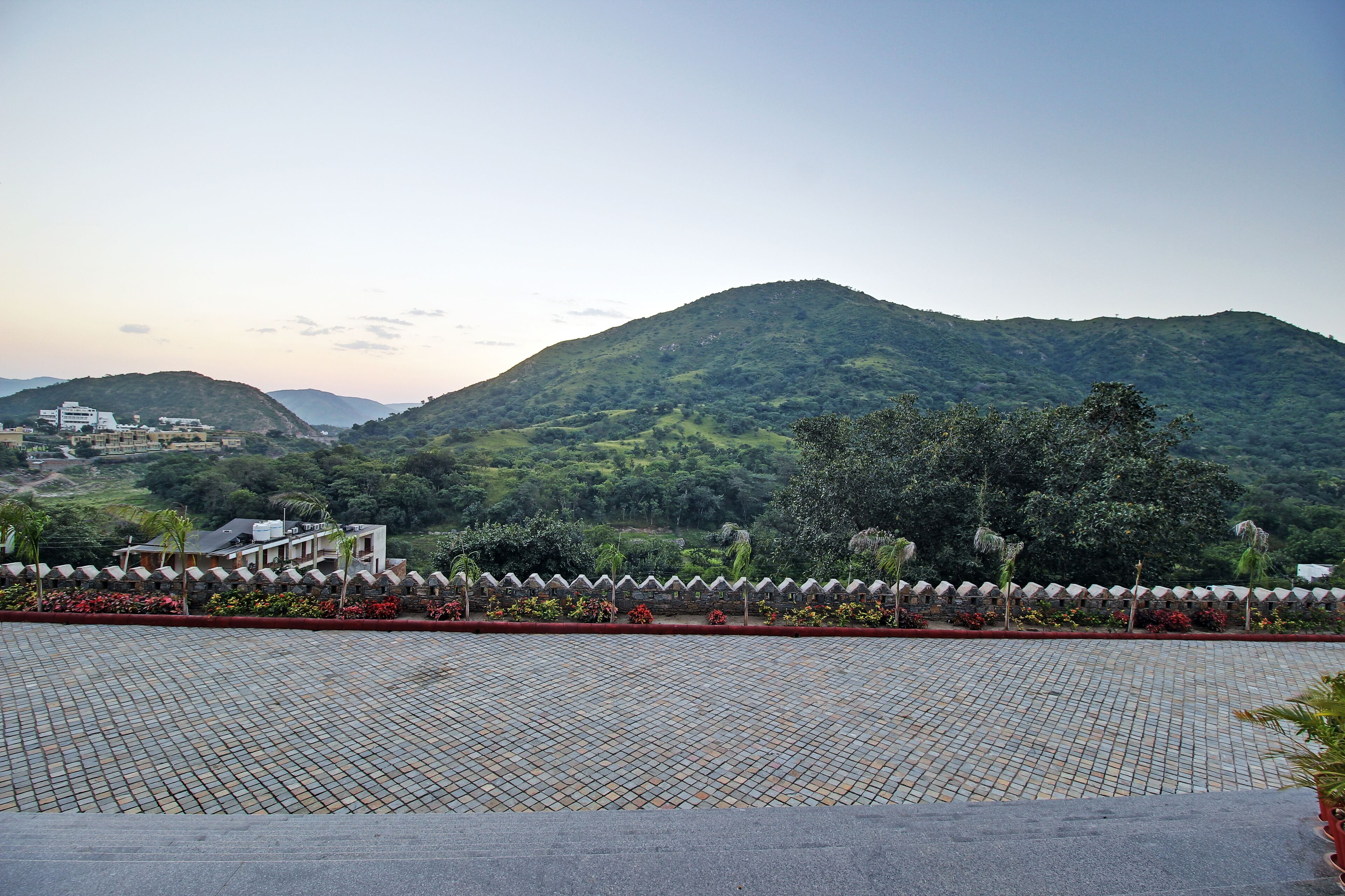 A paved area with a view of a mountain and buildings in the background.