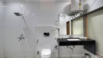A modern bathroom with a toilet, sink, mirror, and shower.