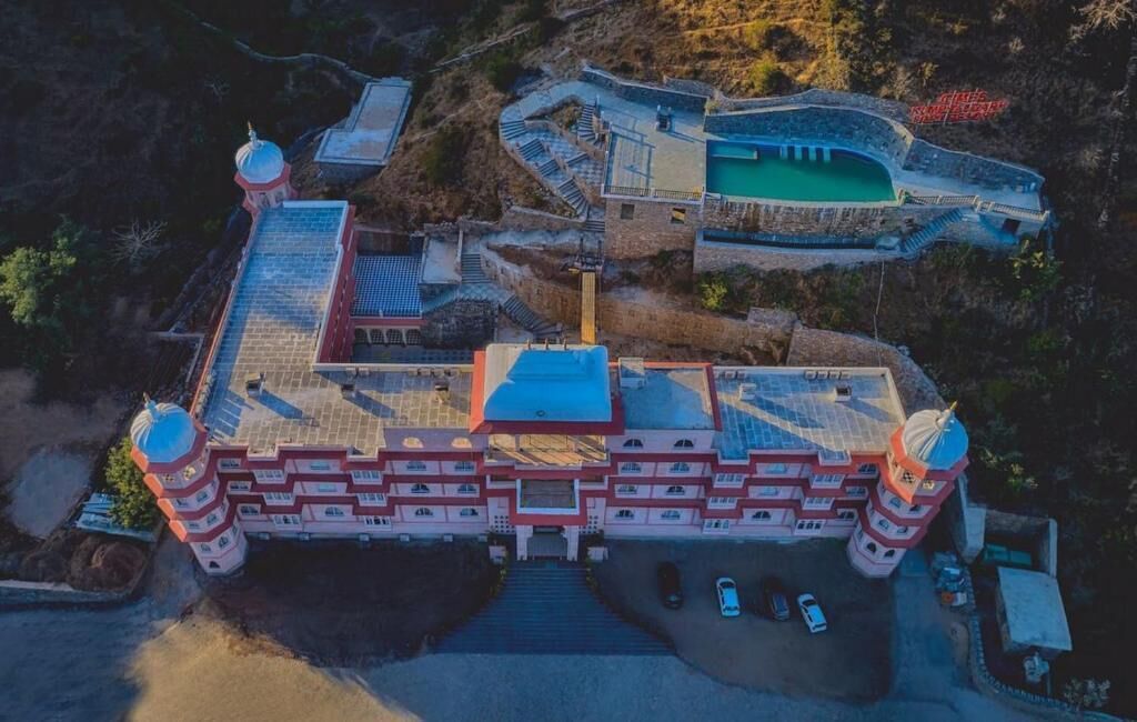Vista aérea de un edificio grande de varios pisos con un patio central, múltiples escaleras y una piscina.