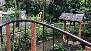 A greenhouse with various plants, a small pond, and outdoor seating. - Famous Inn (Tagaytay)