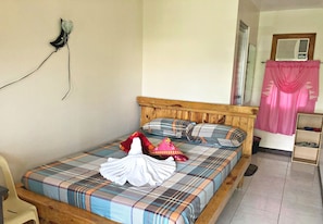 A bed with a plaid bedspread, pillows, and a white towel.