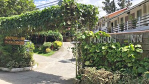 A hotel entrance with a sign for 'Famous Inn' and a sign for 'Atis Inn Tagay Tax City'. - Famous Inn (Tagaytay)