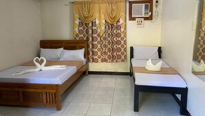 A hotel room with two wooden beds, a patterned curtain, a wall-mounted air conditioner, and a sign about social distancing. - Famous Inn (Tagaytay)