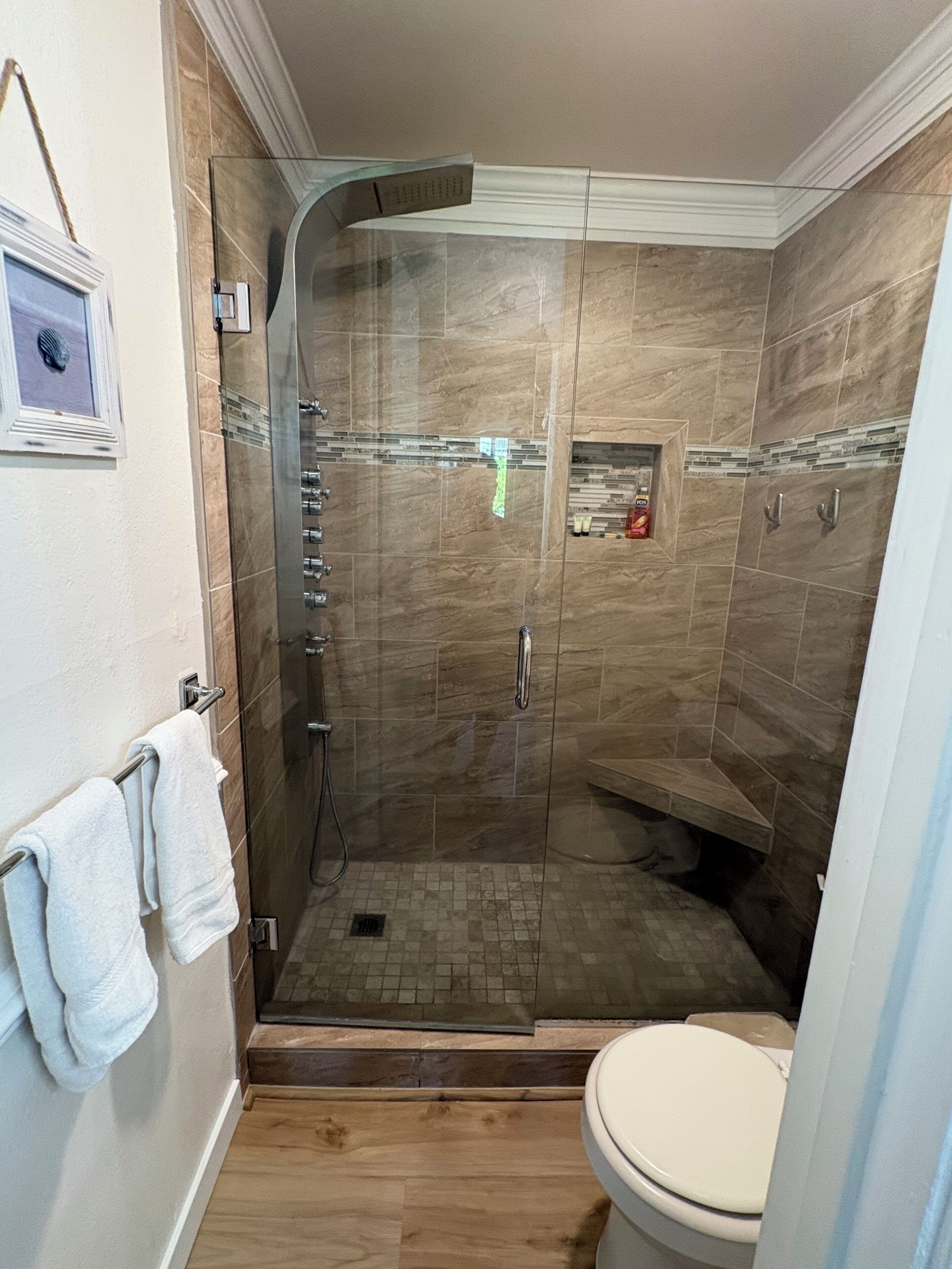 A shower with a glass door, a toilet, and a towel rack with towels.