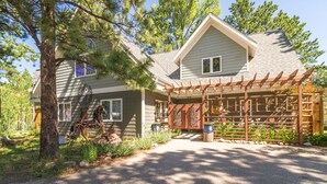 A two-story house with a covered porch and a horse statue. - Sublime luxury  getaway riverfront downtown location great rates  (Estes Park)