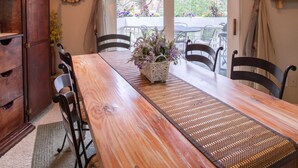 A dining area with a wooden table, chairs, a hanging light fixture, and a view through a glass door to an outdoor patio. - Sublime luxury  getaway riverfront downtown location great rates  (Estes Park)