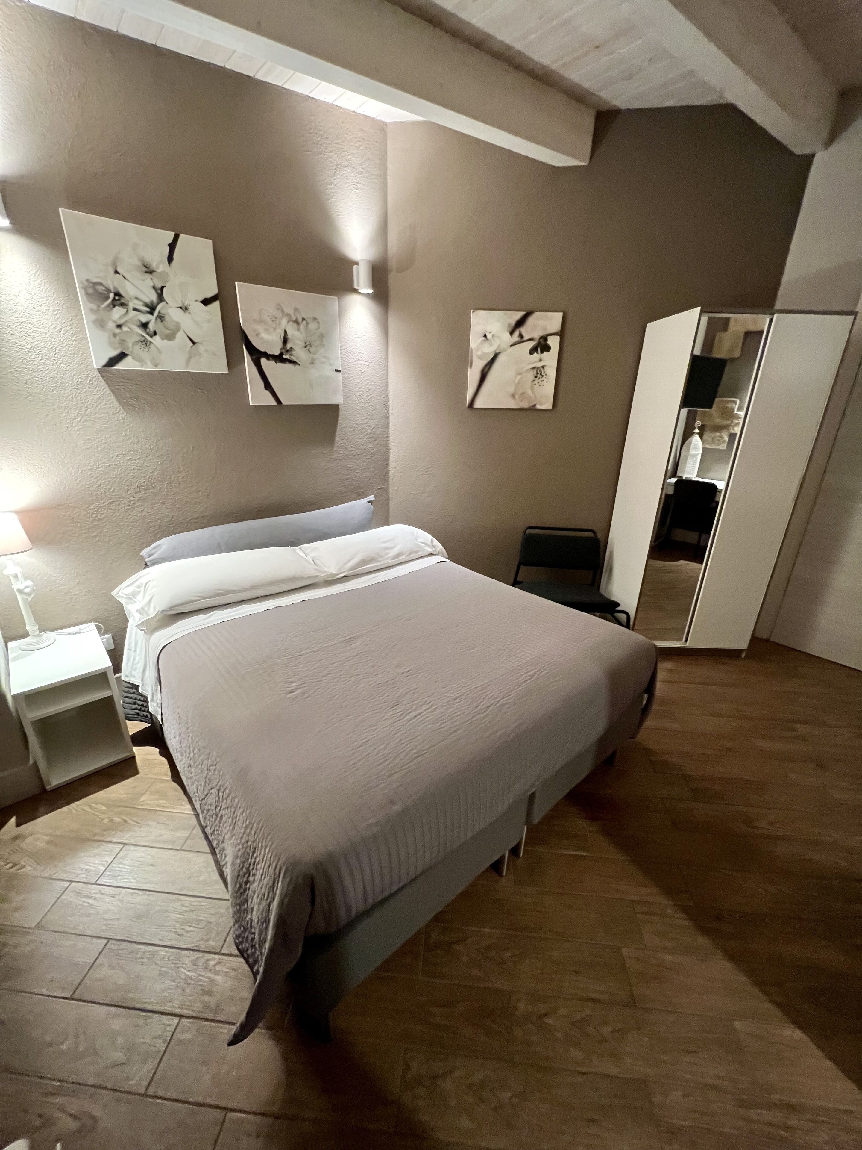 Un dormitorio con cama, mesita de noche y un cuadro colgado en la pared.