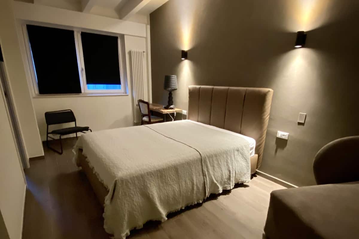 A bedroom with a bed, a chair, a desk, and a lamp.