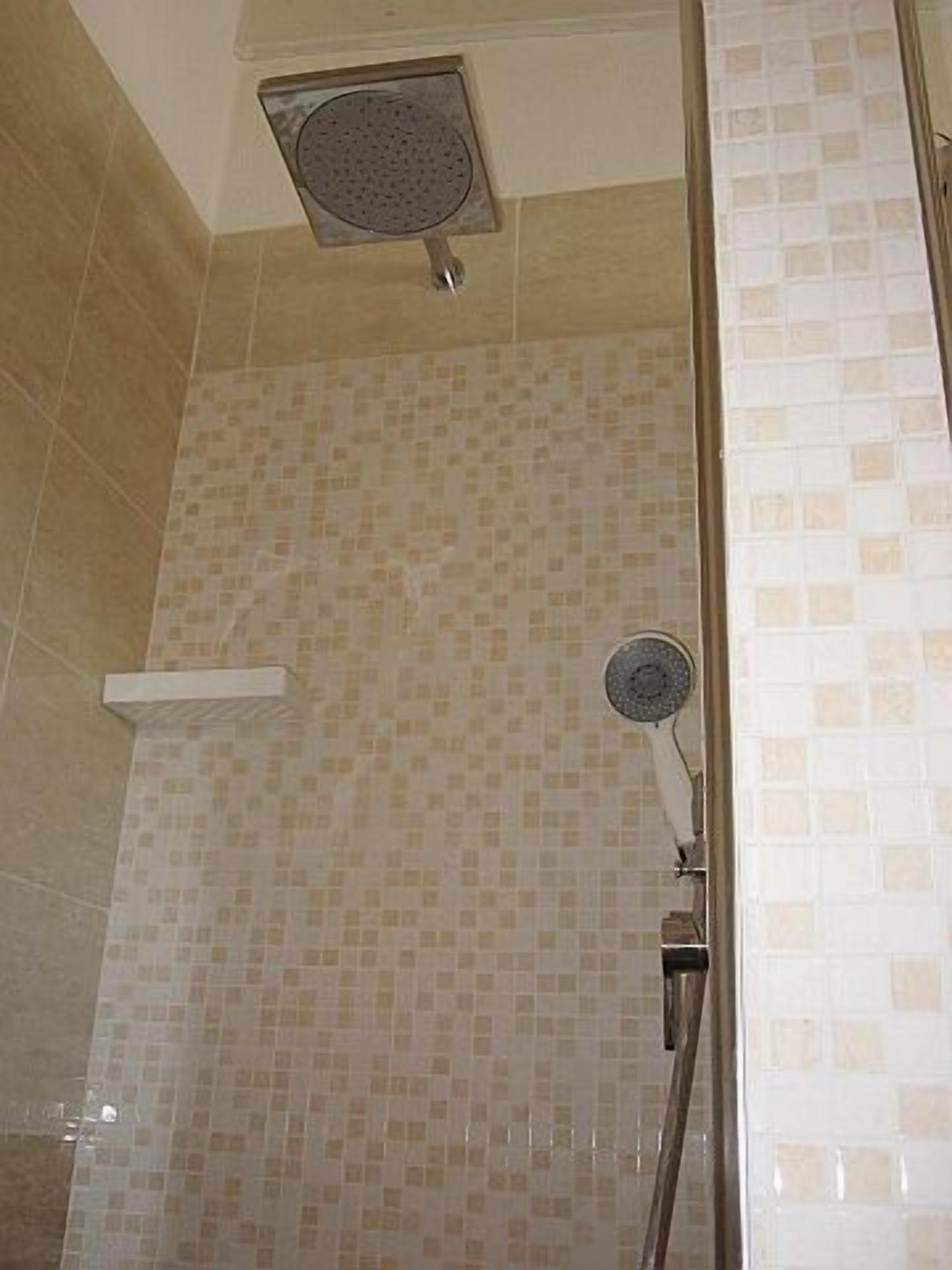 Zona de ducha con paredes de azulejos y un cabezal de ducha instalado en el techo.