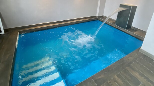A rectangular indoor pool with a clear blue water surface, surrounded by wooden flooring and white walls. - Hotel Bella Napoli (Foggia)