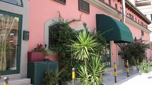 A pink building with a green awning, a door with a 'No Entry' sign, and potted plants in front. - Hotel Bella Napoli (Foggia)