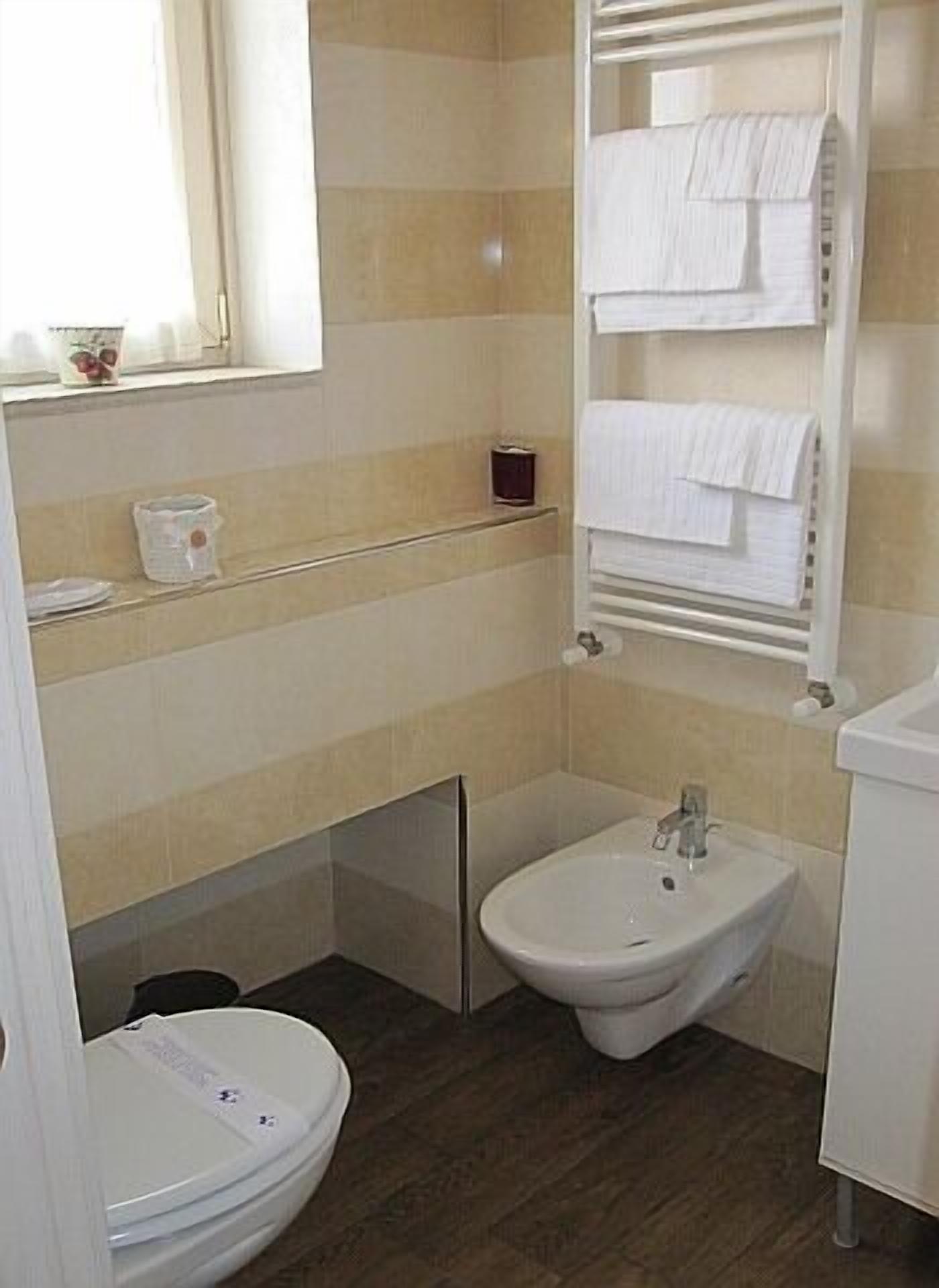 Un bagno piccolo con il water, un bidet e un appendi asciugamani.