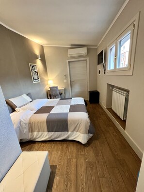 A bedroom with a bed, bedside table, lamp, and a window. - Hotel Bella Napoli (Foggia)