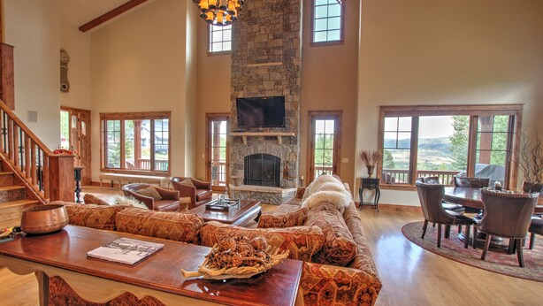 Un salón espacioso con chimenea de piedra, ventanas amplias y un techo alto.