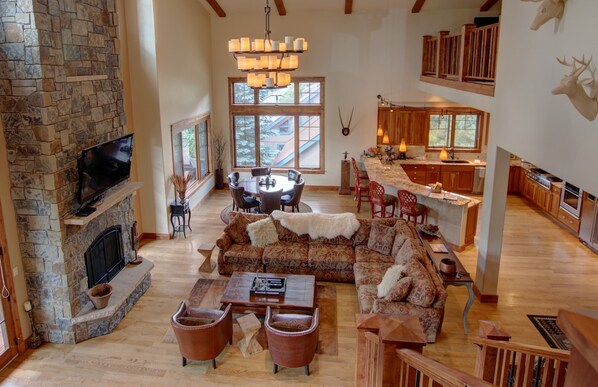 A spacious living room with a stone fireplace, a large sofa set, and a dining area with a chandelier.